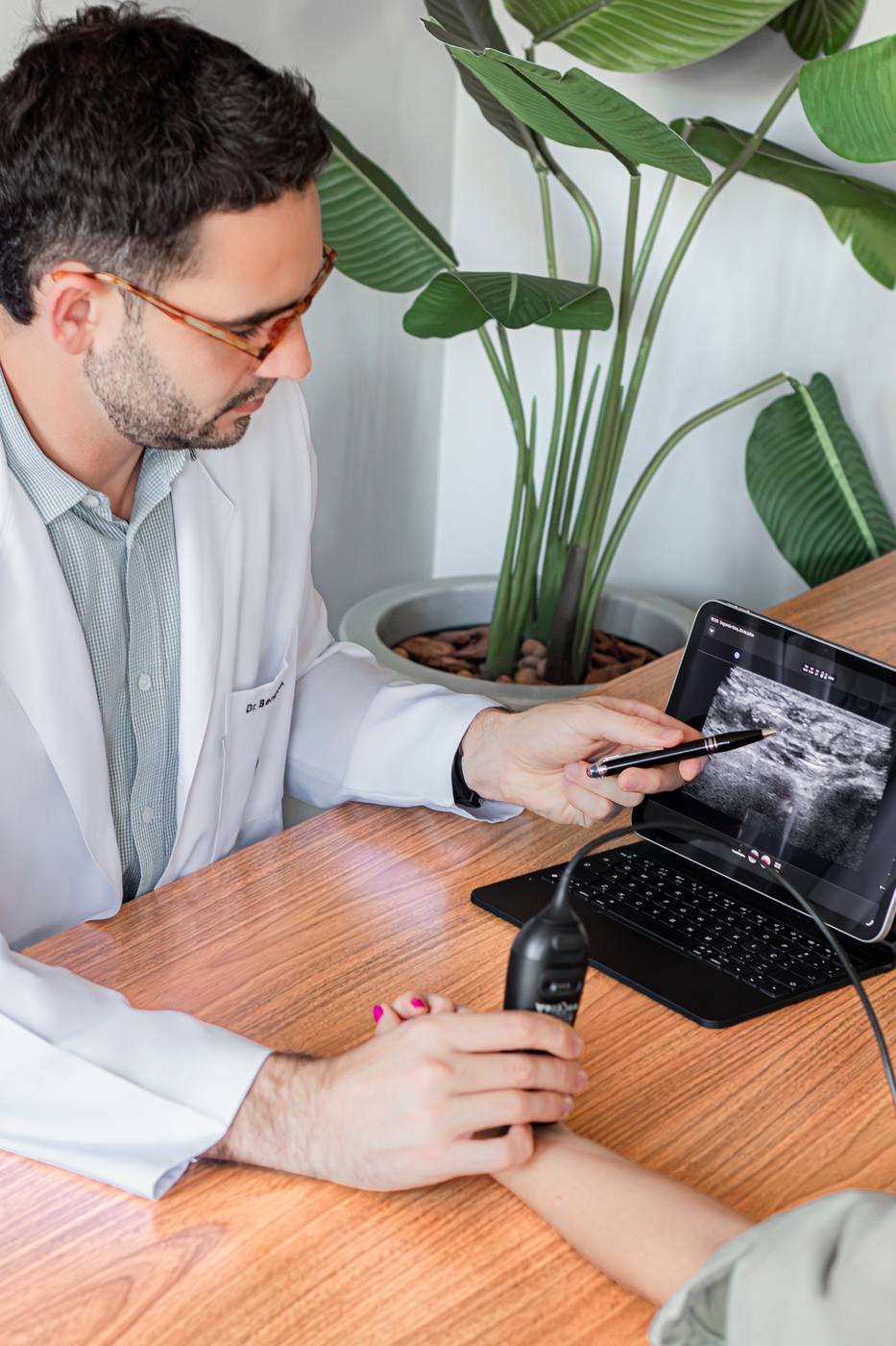 Dr. Bernardo Corrêa avaliando o punho de uma paciente com ultrassom no consultório